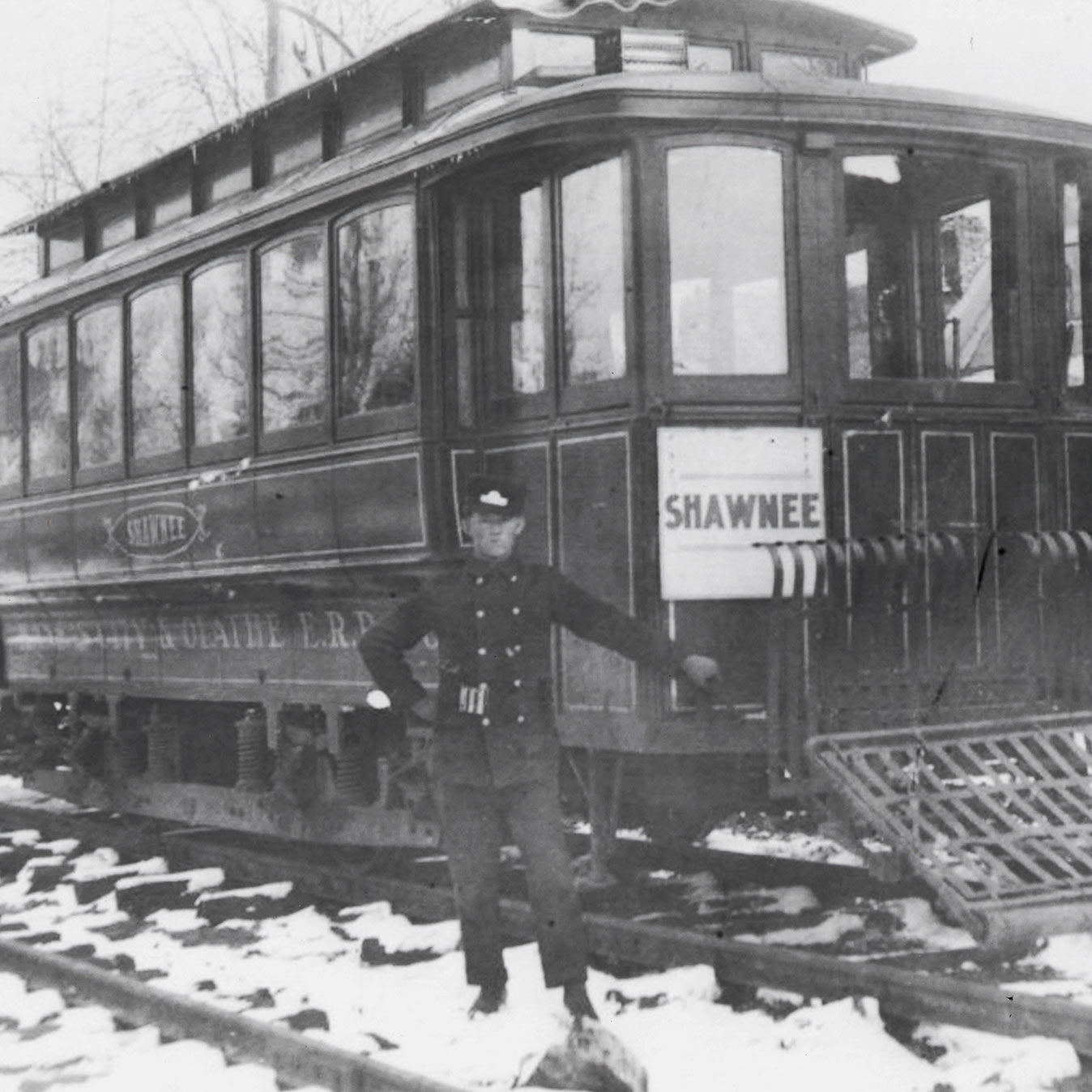 a historic image of a man in front of an electric train